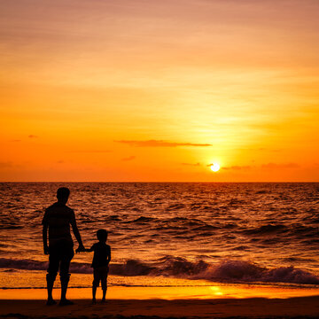Silhouettes of parent and child at sunset on Chilaw Beach, Sri Lanka