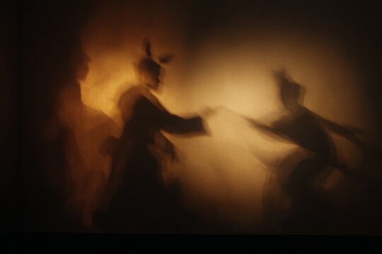 Shadow theatre silhouettes forming animated figures for dramatic storytelling background and stage performance concept
