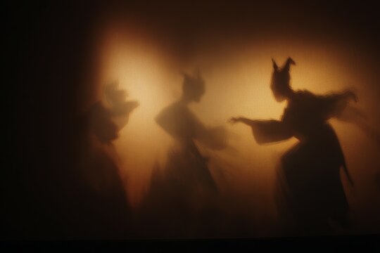 Silhouetted shadow theatre scene with dancing figures and puppets for storytelling performance background