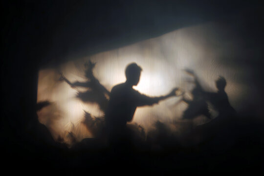 Silhouetted shadow theatre performers projected on a screen for dramatic storytelling background and stage poster use