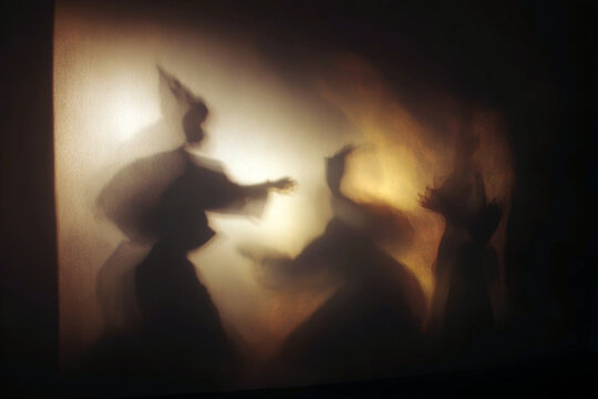 Shadow theatre silhouettes storytelling scene for drama poster and theatrical background with soft warm lighting and mysterious figures
