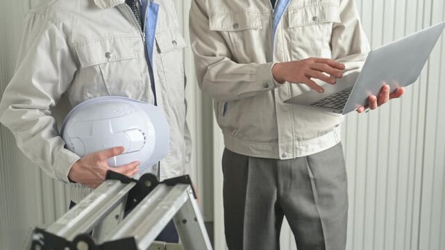 打ち合わせする男性作業員のグループ。建設、工事、工場、業者、相談、会議、DX、修理、点検、建築、内装