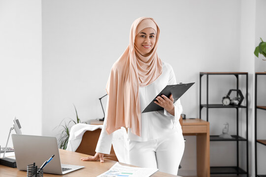 Muslim businesswoman with clipboard in office