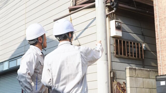 住宅を点検する男性作業員のグループ。建築、工事、外壁、修繕、修理、保守、メンテナンス、チームワーク