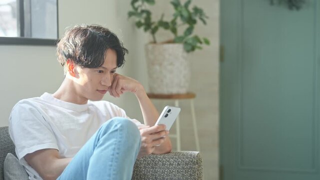 スマホを使う男性。アプリ、SNS、動画、メール、DX、ゲーム、リラックス、若者、検索、スマートフォン