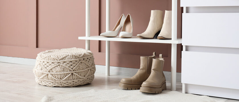 Stylish Women's shoes and boots on a white shelf with a macrame pouf and dresser in a modern room, Women's high heels and ankle boots are neatly arranged on a white shelving unit