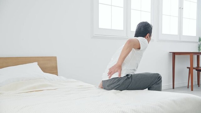 腰痛に悩むシニア男性。ぎっくり腰、ミドル、中高年、老化、加齢、痛み、困る、ヘルニア、ベッド、健康