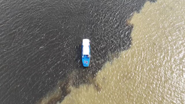 Cinematic high-angle shot of a tour boat at the unique river junction of Orinoco and Caroni in Venezuela.