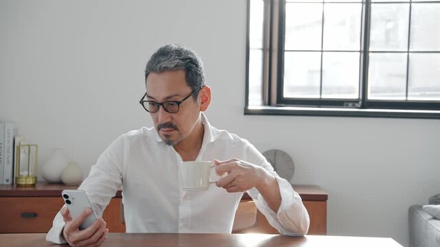 スマホを見るミドル男性。カフェ、くつろぐ、リラックス、アプリ、SNS、動画、メール、情報、ニュース