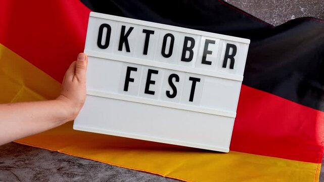 Lightbox with text OKTOBERFEST National symbol of Germany. German wave silky flag background. Concept of traditional beer Bavarian festival. Travel to germany, visit munich european tourism German
