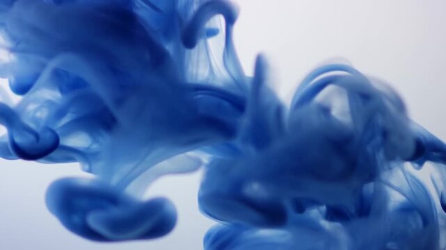 Deep blue ink blooming and swirling in clear water