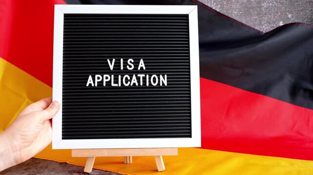 Letter board text VISA APPLICATION National symbol of Germany. German wave silky flag background. Concept of temporary work permit employment migration
