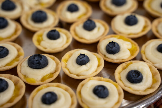 Close up of mini blueberry cream tartlets on tray.