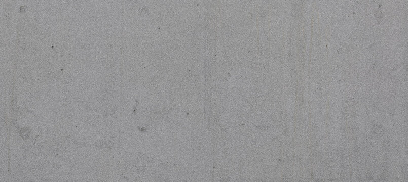 A close-up view of a uniformly textured gray concrete surface, showcasing a smooth finish with subtle variations in tone and small imperfections.