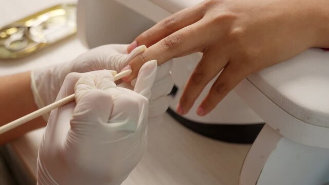 Professional manicurist pushing cuticles during nail treatment