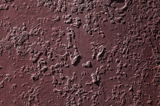 Violet textured background with rust and paint cracks. Reddish-brown base. Raised patches of paint. The aged surface of the steel sheet. Natural shadows