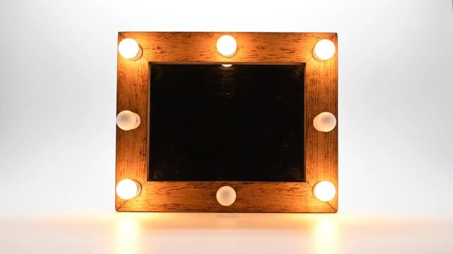 Wooden framed mirror with bright white bulbs turning on and off against a white backdrop