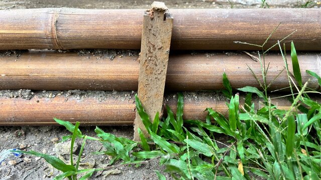 Close-Up of Wooden Poles Surrounded by Green Grass and Soil
