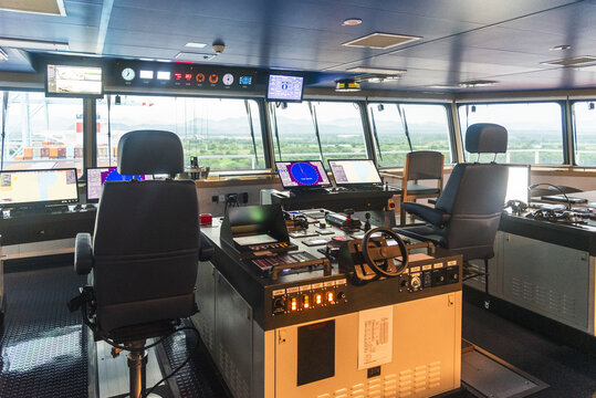 Modern vessel bridge control room with multiple navigation displays, radar screens and electronic systems used by ship officers.