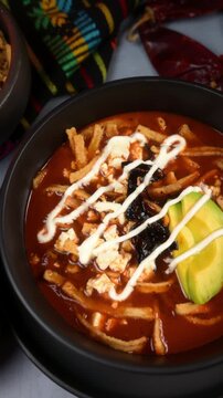 Aerial view of authentic Aztec soup or sopa Azteca served with crispy tortilla strips, fresh cheese and cream. Mexican food