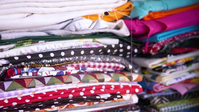 Many colorful fabrics with different patterns and textures stacked in a textile shop