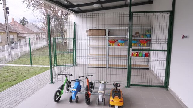 Outdoor storage area at a daycare with children's ride-on toys and sand play accessories
