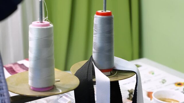 Professional sewing machine working with two spools of thread unwinding in a textile factory