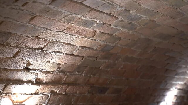 Light moving across an old arched brick ceiling in a dark cellar or tunnel