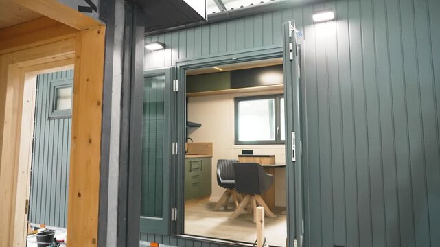 Modern and compact modular tiny house interior with a home office space and a small kitchen