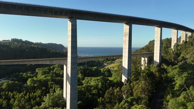 Wide aerial view of La Concha de Artedo viaducts above forest and sea