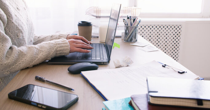 Office woman. Distance work. Unrecognizable entrepreneur typing notes on laptop at desk at professional workplace indoor.