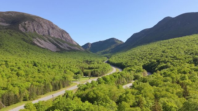 Highway crossing green mountain forest in Franconia Notch State Park, White Mountain National Forest in New Hampshire, United States. Aerial forward, copy space