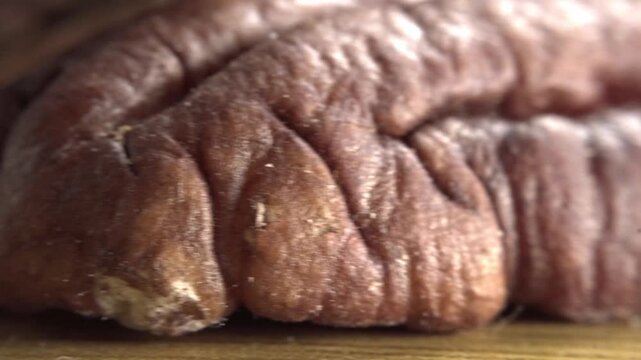 Macro close up of pecan nut highlighting natural wrinkled texture and rich brown color. Detailed food footage showcasing organic ingredient, nutrition and natural surface patterns