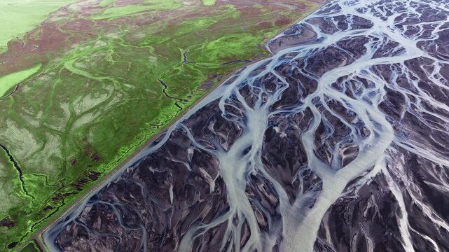 Abstract patterns of braided glacial rivers contrasting with green earth. Aerial