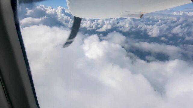 Aerial view from small propeller airplane window flying through white fluffy clouds in Fiji, South Pacific