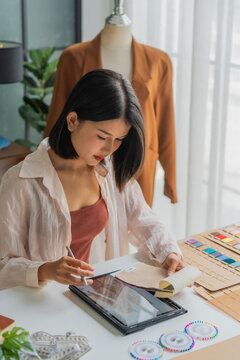 Asian woman designer using tablet design cloth