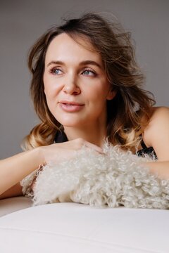 Thoughtful woman. Beauty portrait. Elegant female relaxing on white sofa resting on soft cushion enjoying peaceful mood quiet lifestyle.
