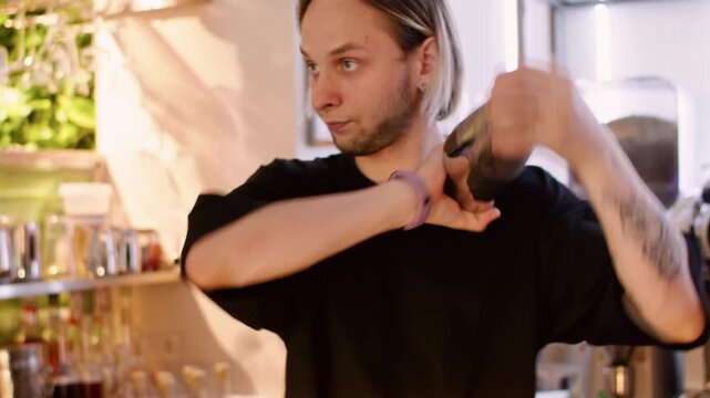 Preparing alcohol drink. Bartender service. Man pouring liquid ingredient in shaker in restaurant bar interior. Professional mixology technique.