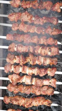 Grilling pork kebab on skewers, cooking. Vertical footage