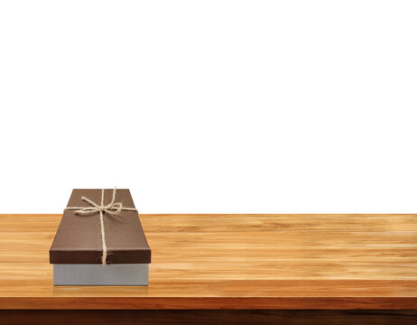 A brown gift box, tied with a jute ribbon, sits on a wooden table PNG transparent.