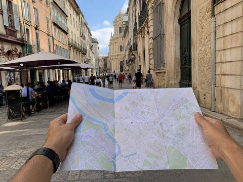 Traveler consults a paper map while exploring a city street, capturing urban tourism, wayfinding, independent travel, sightseeing, and traditional navigation.