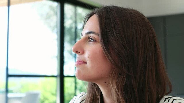 Beautiful young woman looking up with a hopeful and happy expression. Profile view of a graceful female feeling contemplative, optimistic, and smiling with faith while looking at the sky