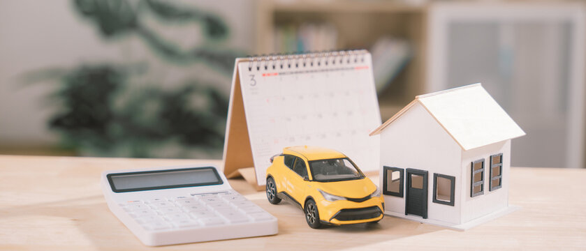 Financial planning for property investment, car loan, home insurance features calculator placed beside house model, calendar helps tracking wealth management, construction, rental, finance