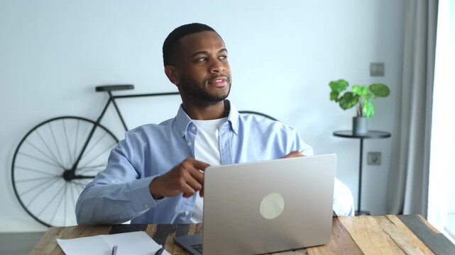 Young african american businessman finishing his project on a laptop. Stretching. And leaning back with satisfaction in a modern office. Enjoying a moment of rest after completing his successful work
