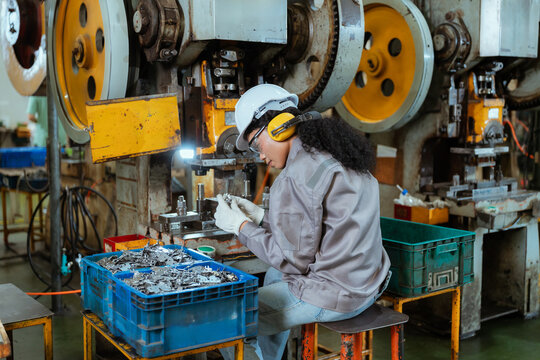 Worker at metal processing facility conducts task with machinery in a factory setting during the day