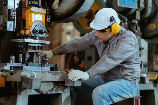 Workers operate machinery in a factory during daytime hours in a production setting with multiple workstations