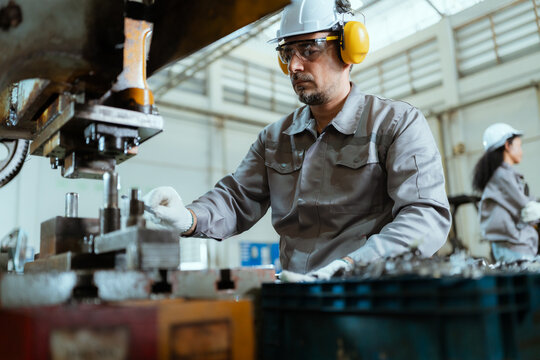 Worker using machinery in a factory setting during daytime