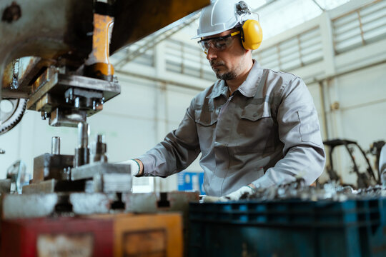 Worker using machinery in a factory setting during daytime