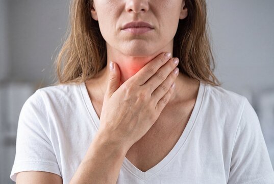 Woman touching her neck feeling pain or sore throat, close up on throat area with red highlight