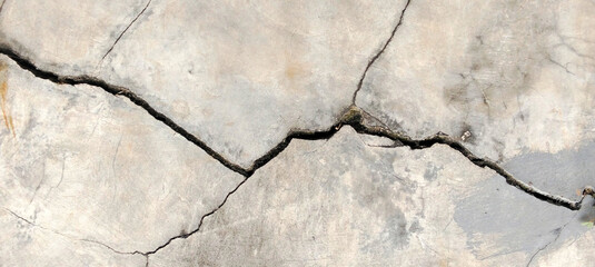 Fototapeta premium Deep diagonal cracks in weathered light colored concrete surface.